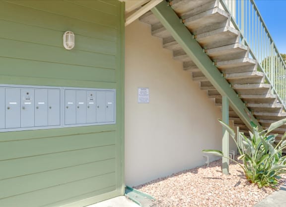 a green building with a staircase and mailboxes next to it
