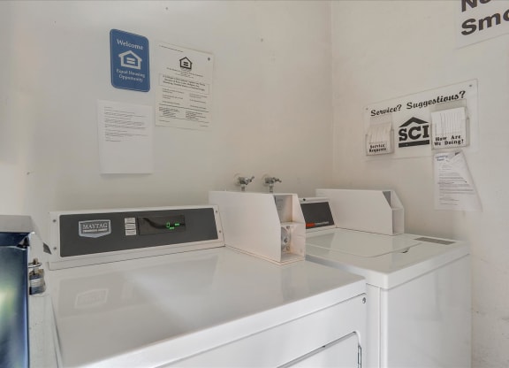 A white washing machine sits next to a dryer in a small room.