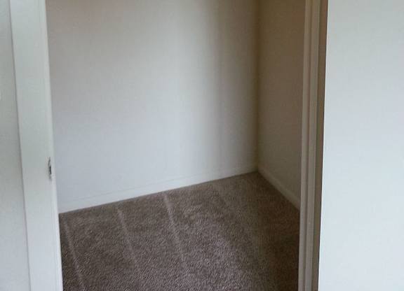A small closet with a carpeted floor and a white door.