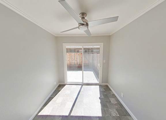 A room with a ceiling fan and a door leading outside.