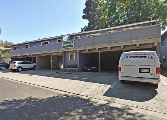 A white van is parked in front of a building with a sign that reads