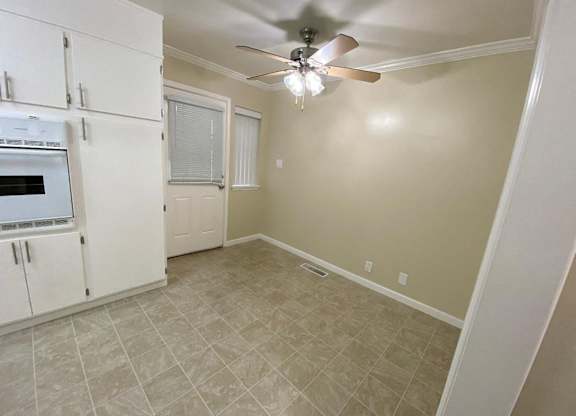 A kitchen with white cabinets and a fan on the ceiling.