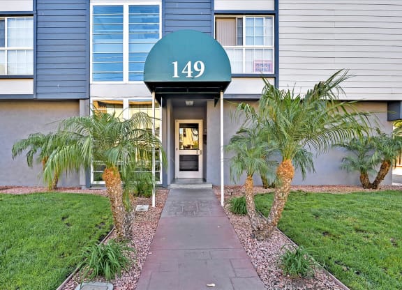 the front entrance to a building with palm trees and a sidewalk