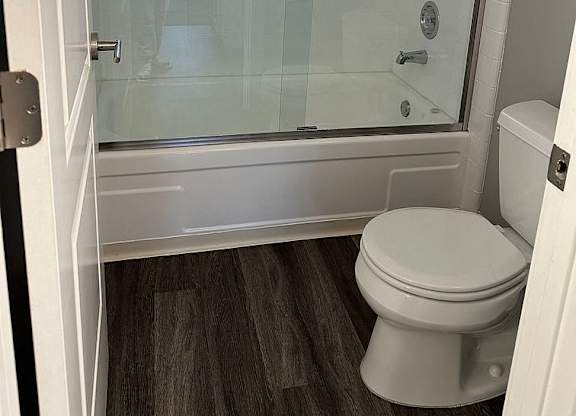 A white toilet sits in a bathroom next to a glass shower stall.