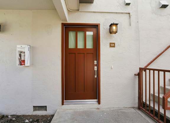A brown door with a glass window is on a white wall.