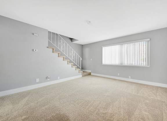 A room with a staircase and a window with blinds.