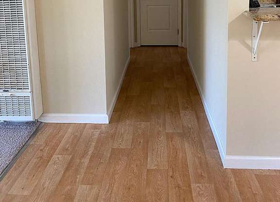 a hallway with a white door and a wood floor