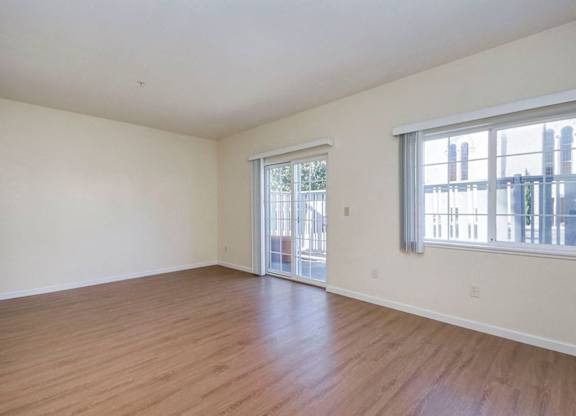 A large empty room with wooden floors and a sliding glass door.