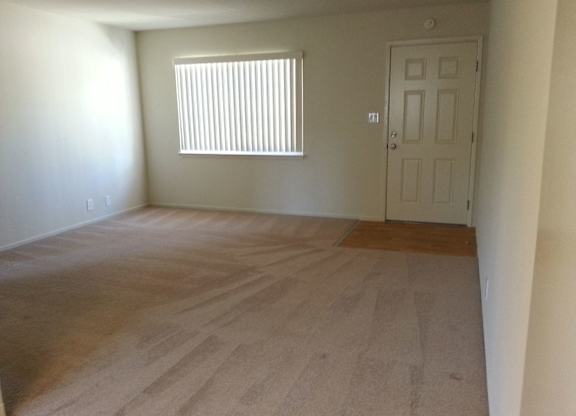 A room with a door and a window with blinds.