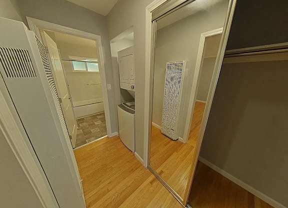 A hallway with a mirror on the wall and a washing machine in the background.
