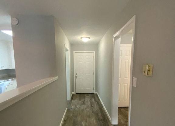 A long hallway with white doors and wood floors.