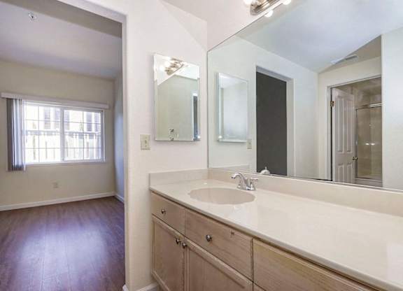 A bathroom with a sink, mirror, and wooden floors.