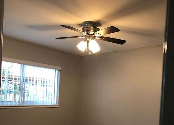 A room with a ceiling fan and carpeted floor.