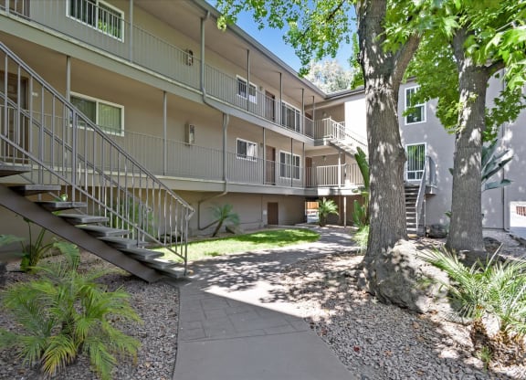 external view of an apartment building with a pathway and trees
