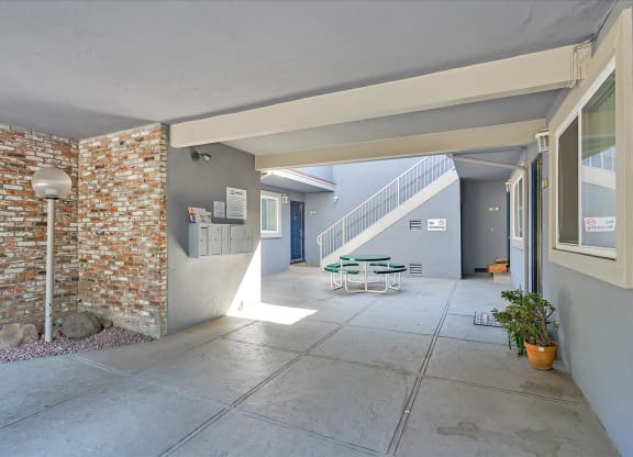 A patio area with a brick wall and a green staircase.