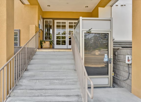 A staircase with a metal railing leads to a glass door.