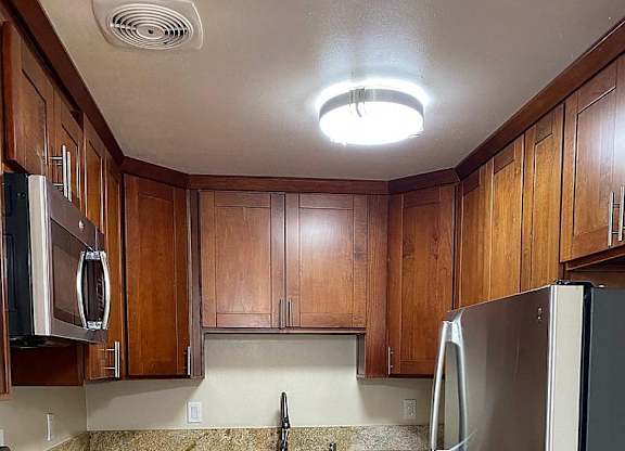 a kitchen with wooden cabinets and a stainless steel refrigerator