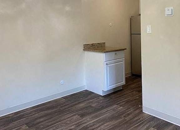 an empty room with a ceiling fan and a kitchen