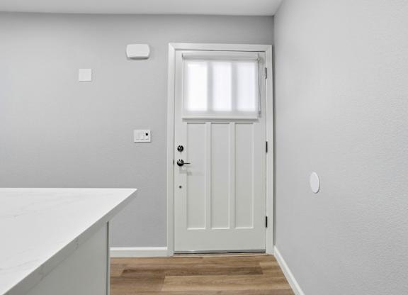 A white door with a window above it in a room.