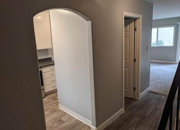 A white door is in a hallway with a brown floor.