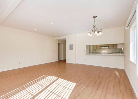 A large empty room with wooden floors and a chandelier.