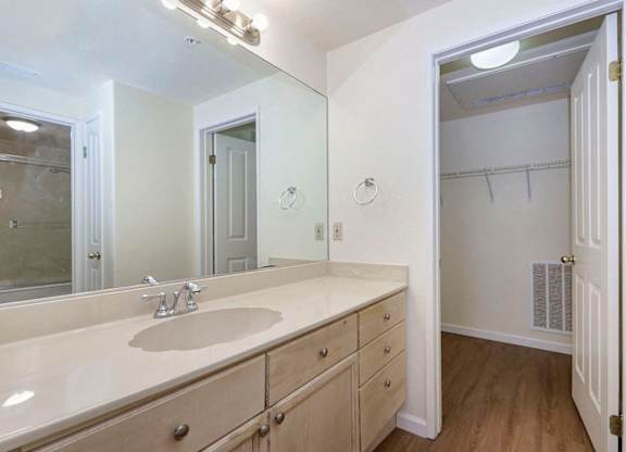 A bathroom with a sink, mirror, and a door.
