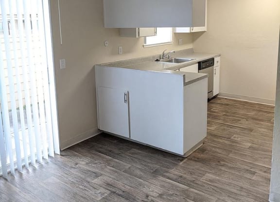 an empty kitchen with a ceiling fan and a window