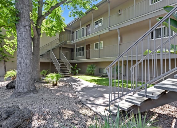 the exterior of an apartment building with stairs and landscaping