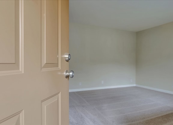an empty room with a door open to a room with carpet
