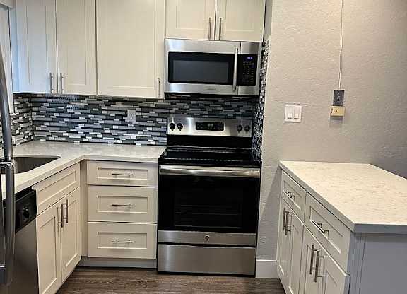 A kitchen with white cabinets and a black stove top oven.