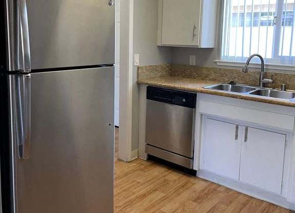 A kitchen with a stainless steel refrigerator and wooden floors.
