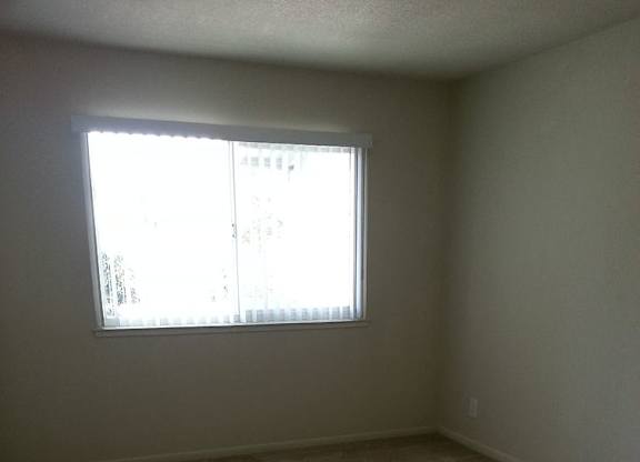 A room with a window and carpeted floor.