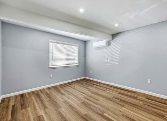 A room with wooden flooring and a window with blinds.