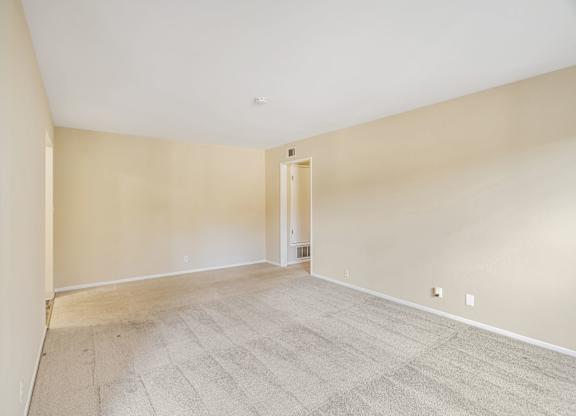 Empty room with carpeted floor and white walls.
