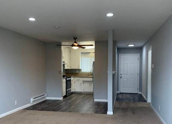 A room with a carpeted floor and a ceiling fan.