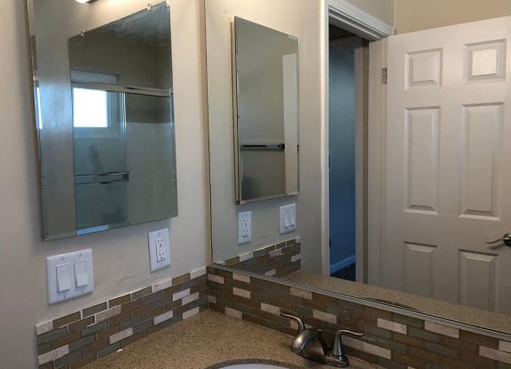 a bathroom with a sink and two mirrors