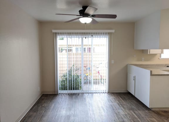 an empty living room with a large window and a ceiling fan