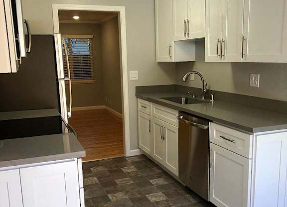 A kitchen with white cabinets and a black refrigerator.