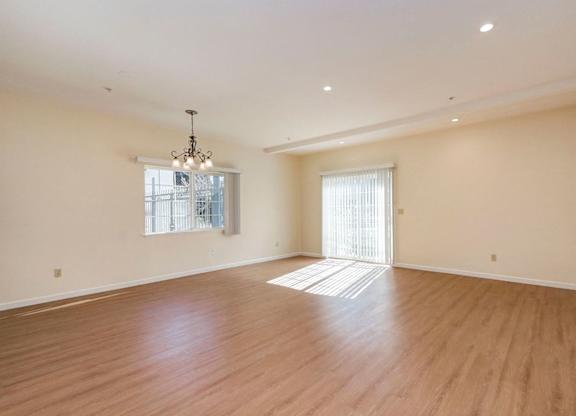 A large empty room with wooden floors and a chandelier.