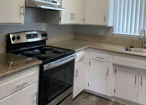 A kitchen with white cabinets and a black stove top oven.