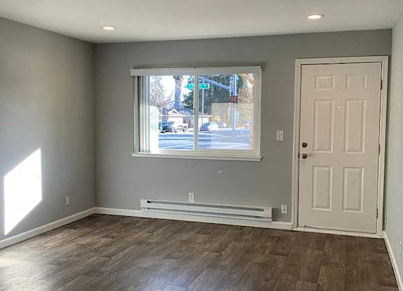 A room with a white door and a window with a view of the street outside.