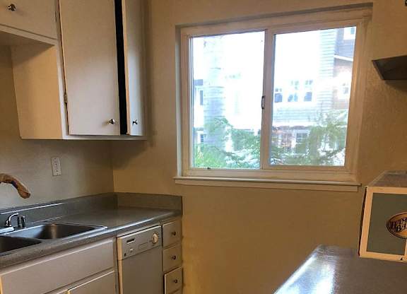 A kitchen with white cabinets and a window.