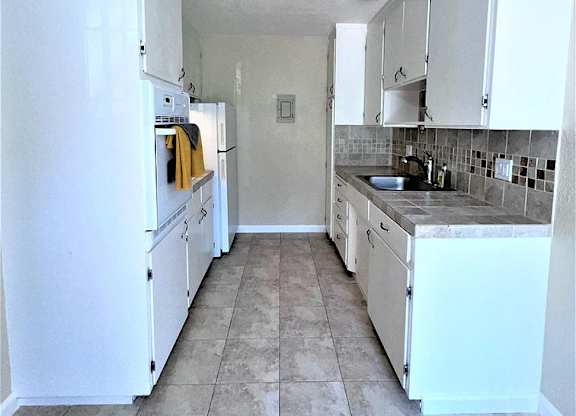 A kitchen with white appliances and cabinets.