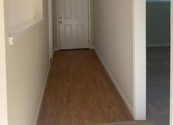 A hallway with a white door and a light on the ceiling.