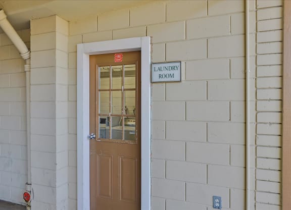 A brown door with a glass window and a sign that says Laundry Room.