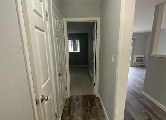 A hallway with white doors and wood flooring.