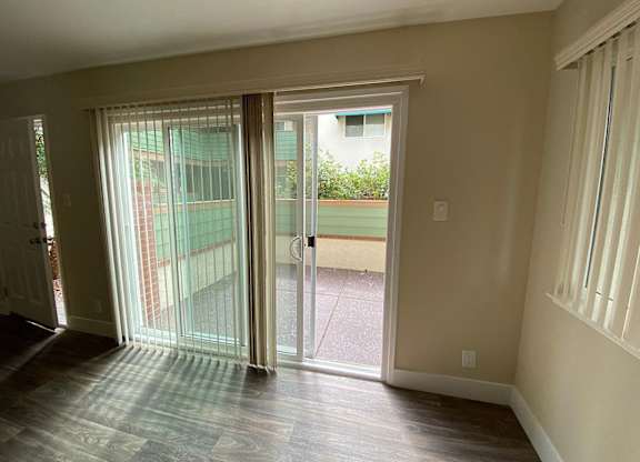 an empty living room with large windows and a ceiling fan