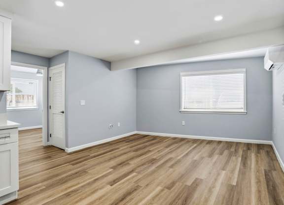 A room with wooden flooring and a window with blinds.
