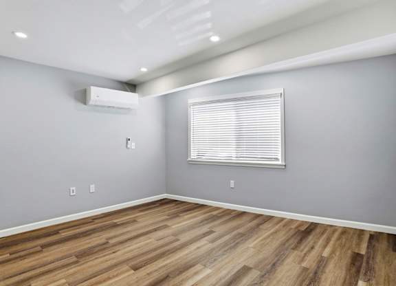 A room with a window and wooden flooring.