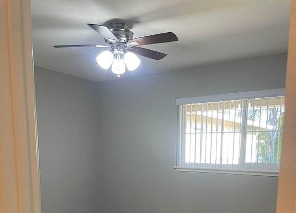 A room with a ceiling fan and a window.